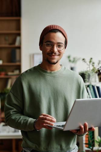 Young confident IT engineer in casualwear using laptop